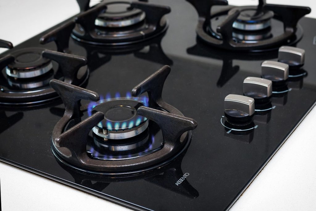orange oil degreaser spray being applied to gas stove surface
