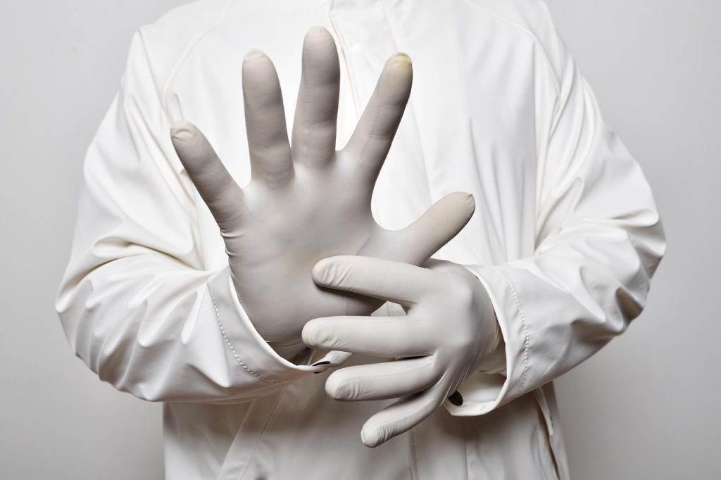 spray bottle with diluted bleach solution next to rubber gloves and mask on table