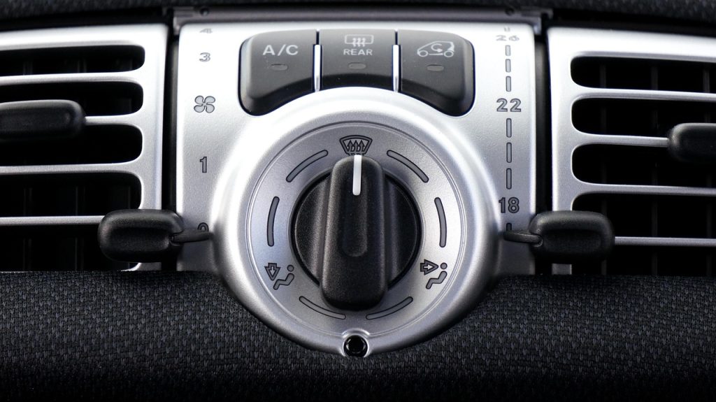 person adjusting air conditioning remote control in a car