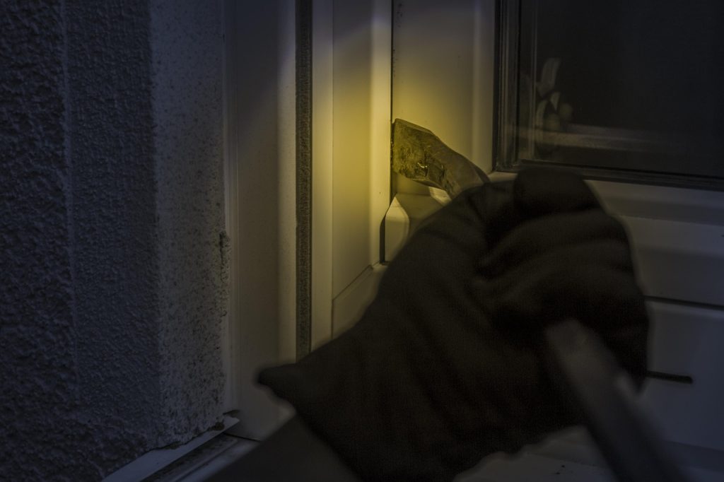 person checking window screen mesh with flashlight at night
