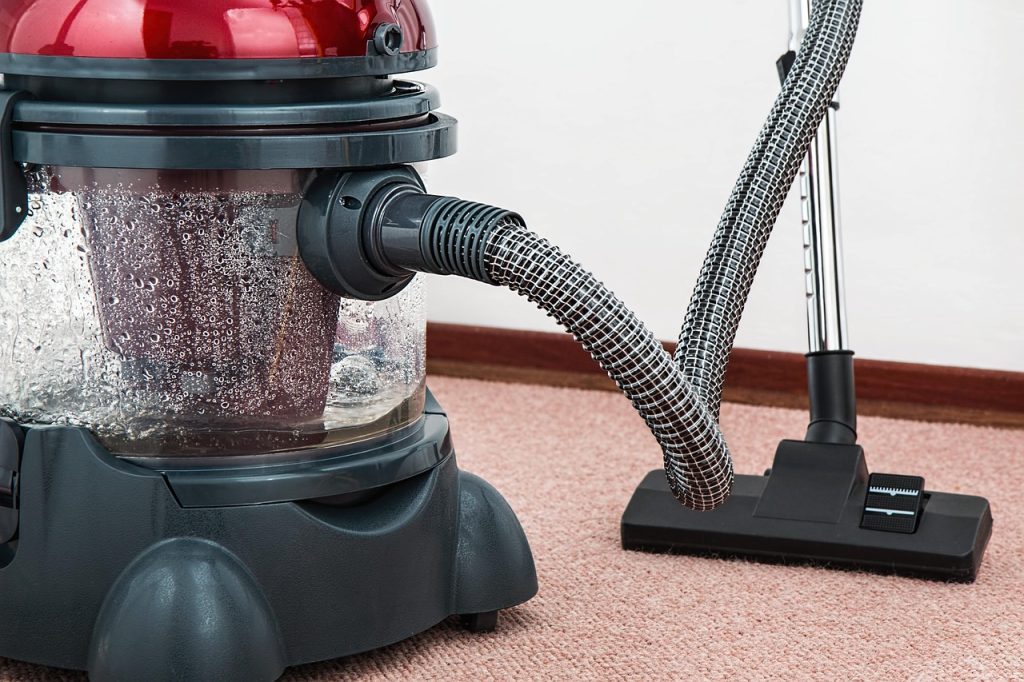 child playing on clean rug while father vacuums nearby