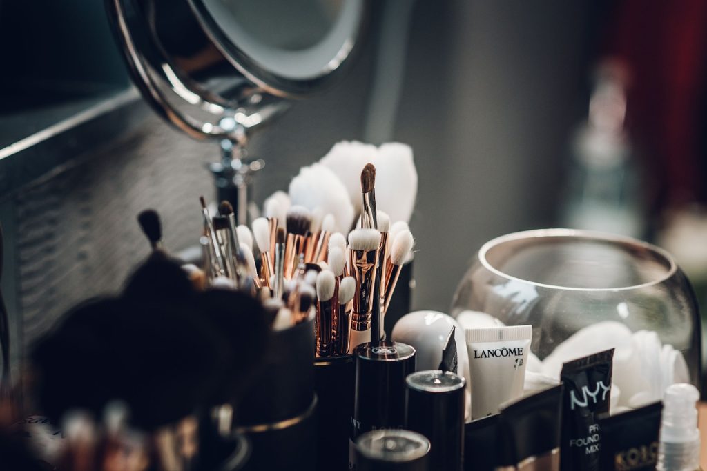 wall-mounted small shelf beside vanity mirror with cosmetics