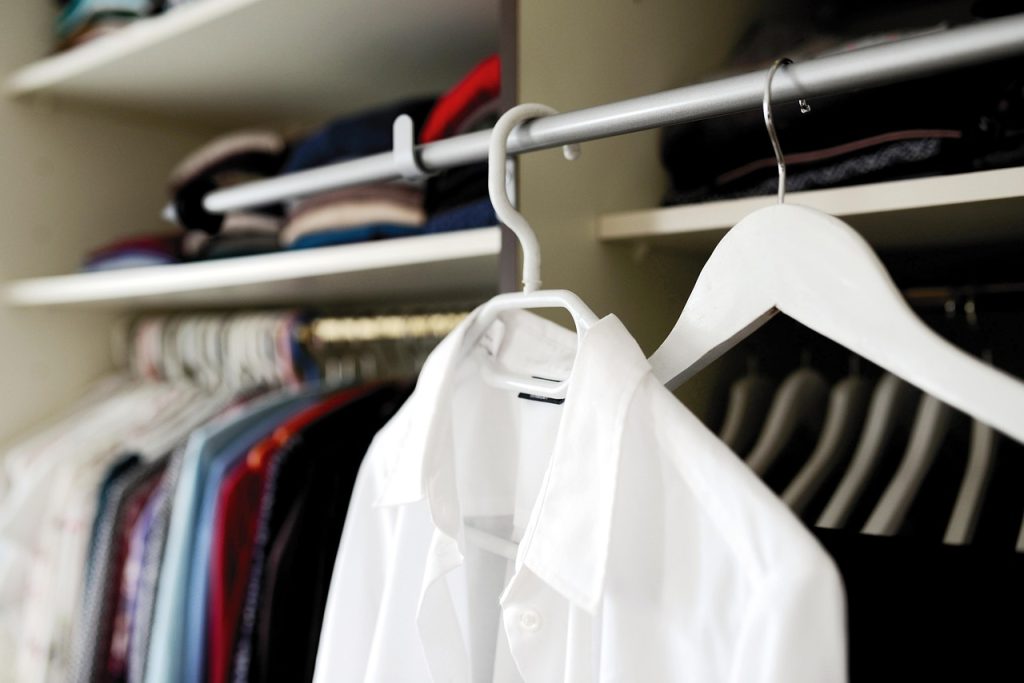 messy closet before hanger replacement with mixed plastic hangers