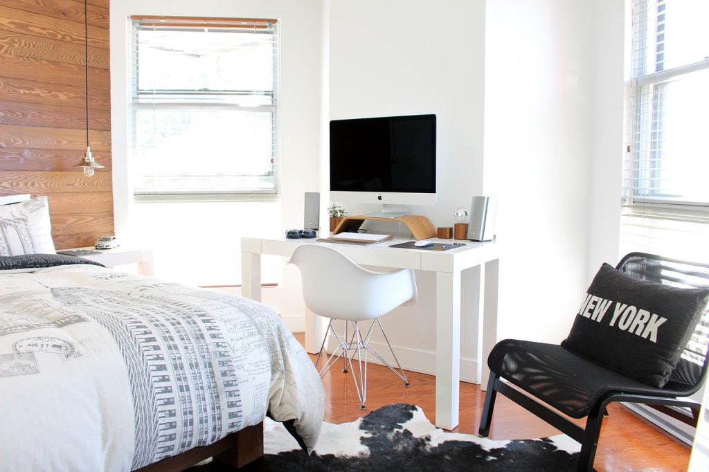 cluttered small bedroom with clothes piled on chair and bed
