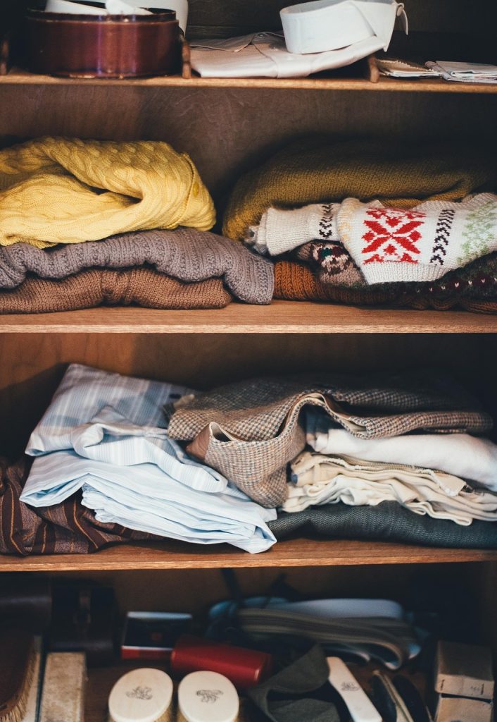 flat storage boxes sliding under bed frame with folded seasonal clothes